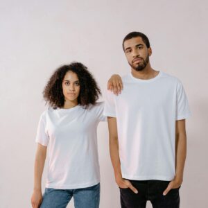 A young man and woman in casual white T-shirts, standing confidently for a fashion photoshoot.