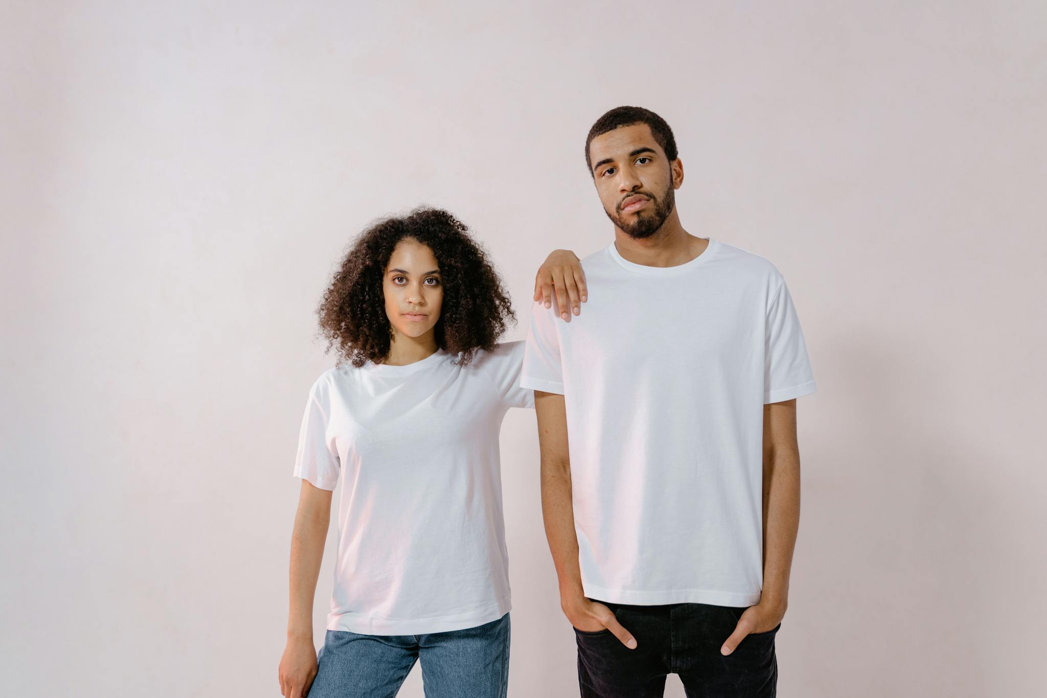 A young man and woman in casual white T-shirts, standing confidently for a fashion photoshoot.